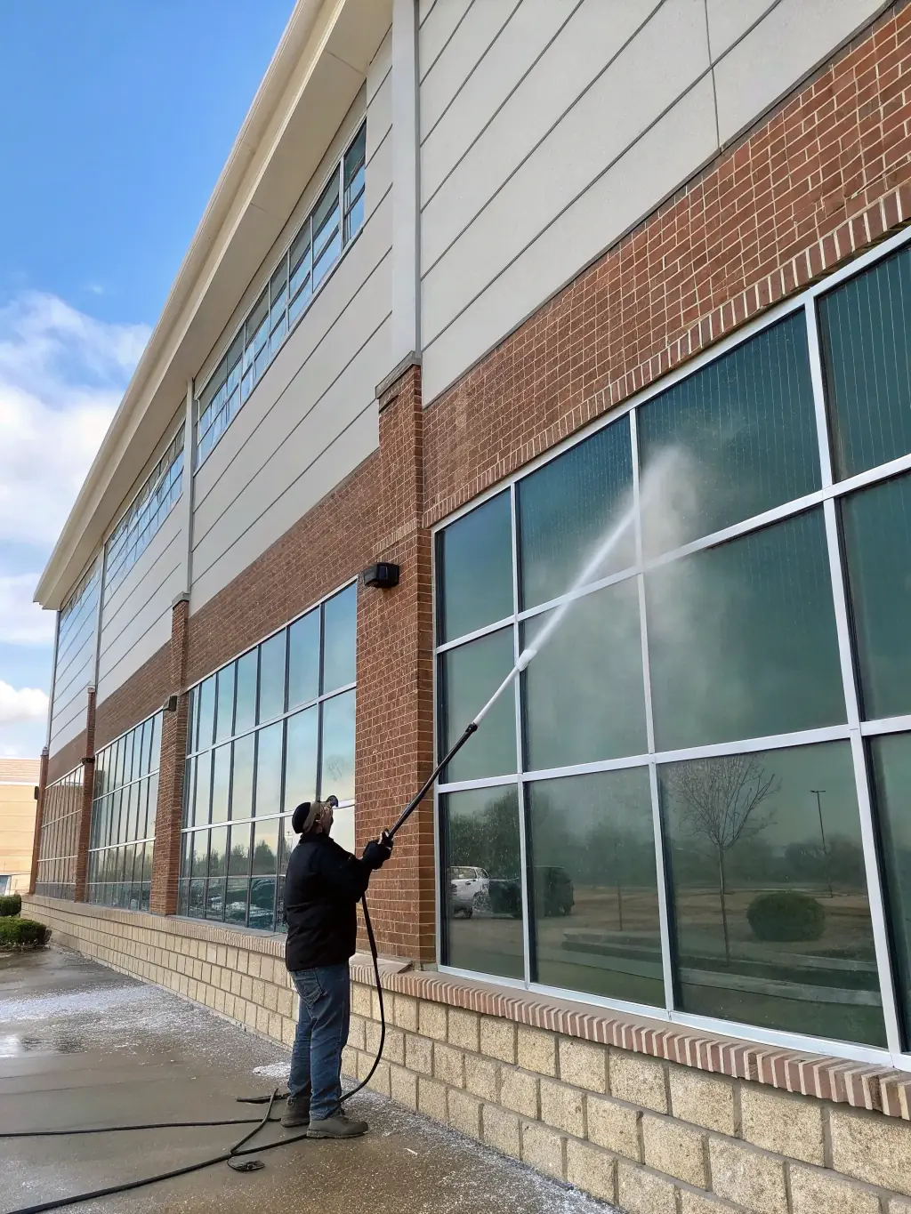 A commercial building's facade being power washed, with a focus on removing graffiti and grime, highlighting Big Rinse Energy's commercial cleaning capabilities.