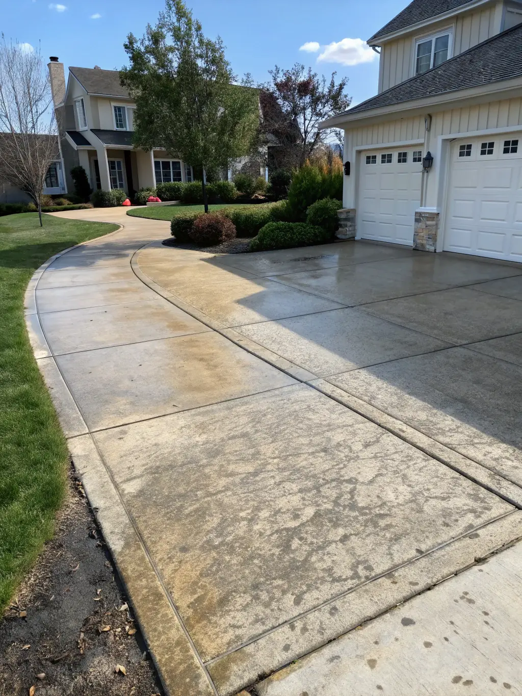 A before-and-after photo showcasing a heavily stained driveway transformed into a pristine surface by Big Rinse Energy's power washing services.